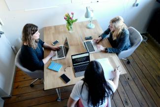 three women sitting and facing each other by CoWomen courtesy of Unsplash.